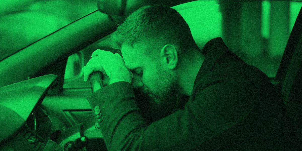 A driver resting his head on the steering wheel of a car