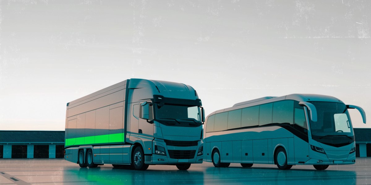 A modern articulated lorry and a coach parked side by side in a depot yard at dawn